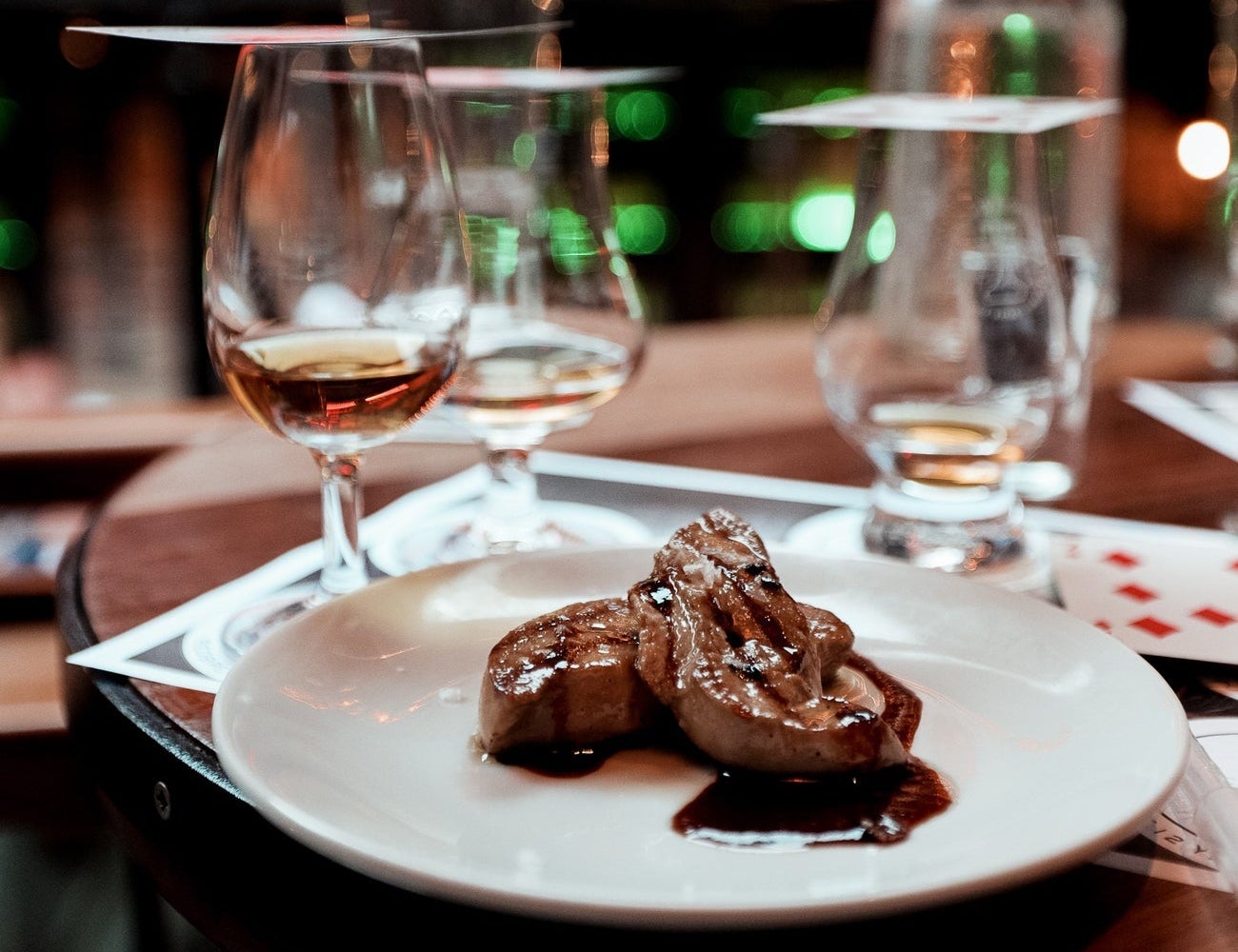 Whiskey glasses and a white plate of food on a wooden table