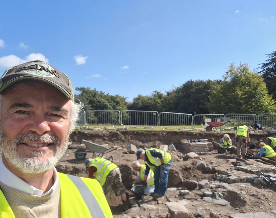 A view of an open excavation trench with several people wearing high visibility vests