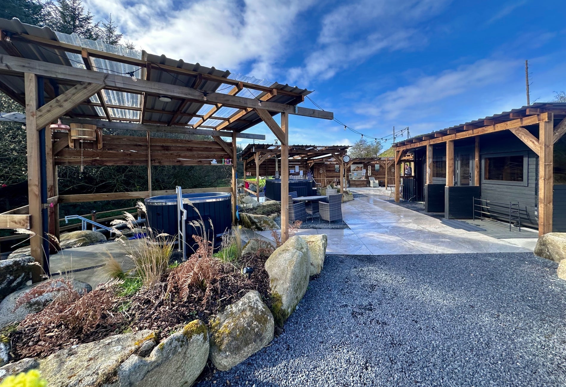 Pathway into an area with mobile sauna units on the right and mobile hot tubs on the left