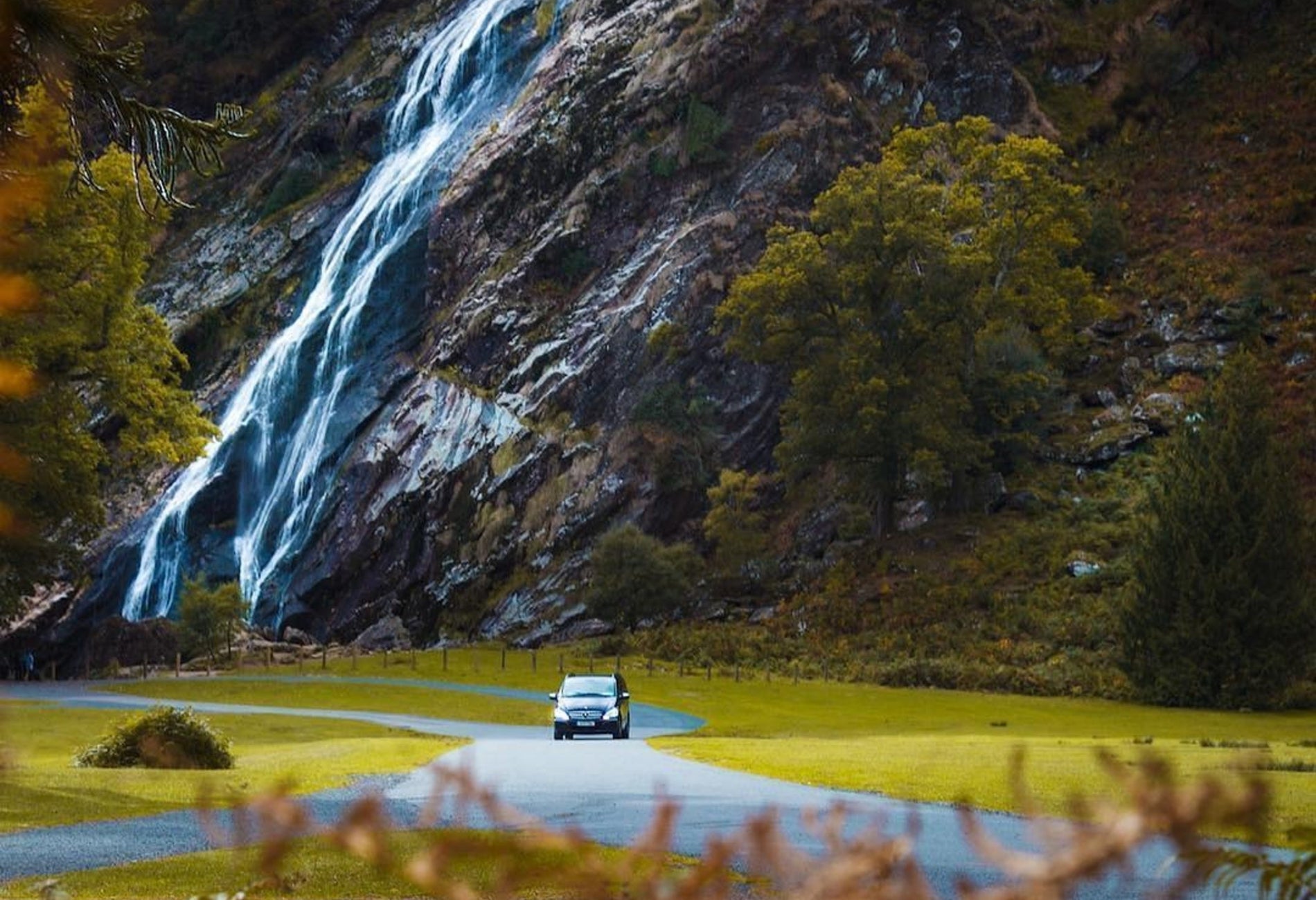 Car driving on a road with a waterfall in the background