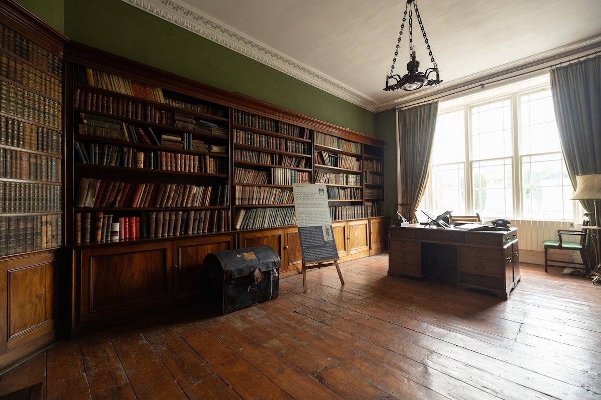 View of a library with wooden book cases and a desk