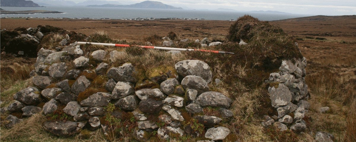 An ancient stone wall with a view beyond of hills and bogland