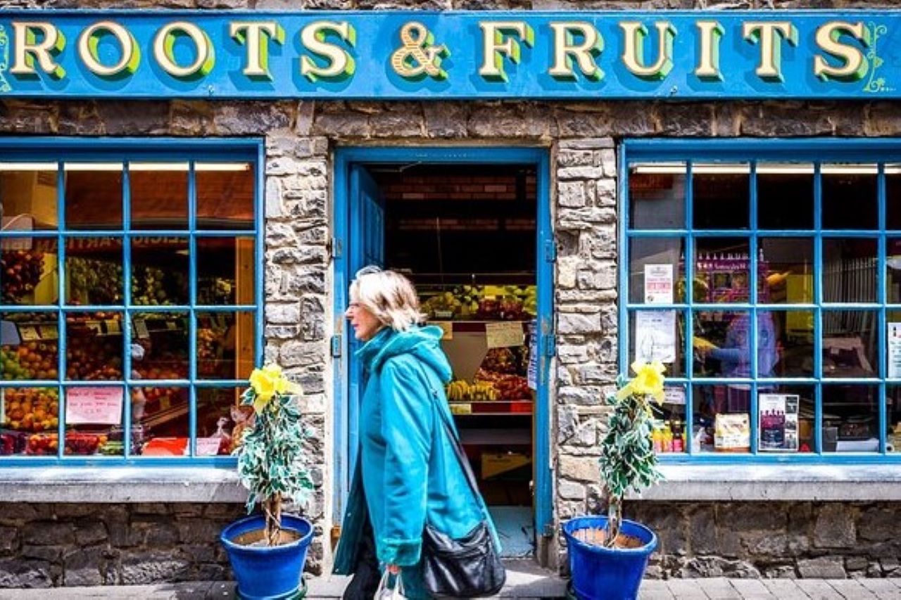 A stone clad shop front with old style green window panes and signage