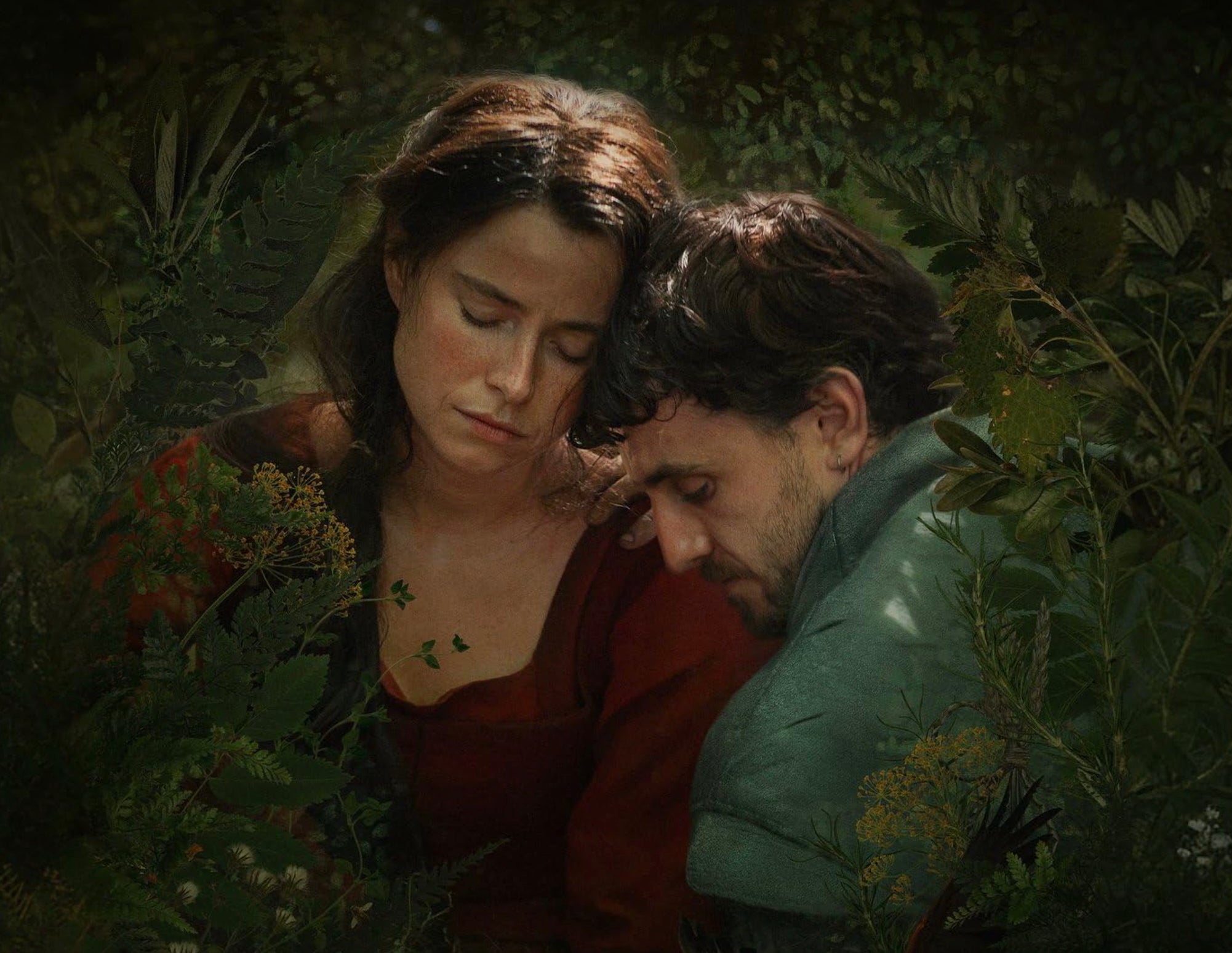 A man and a woman are embracing amongst plants.