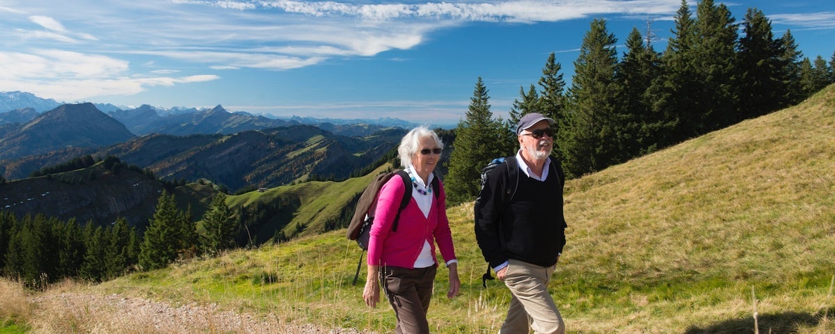 Two adults hike up a hill in the countryside