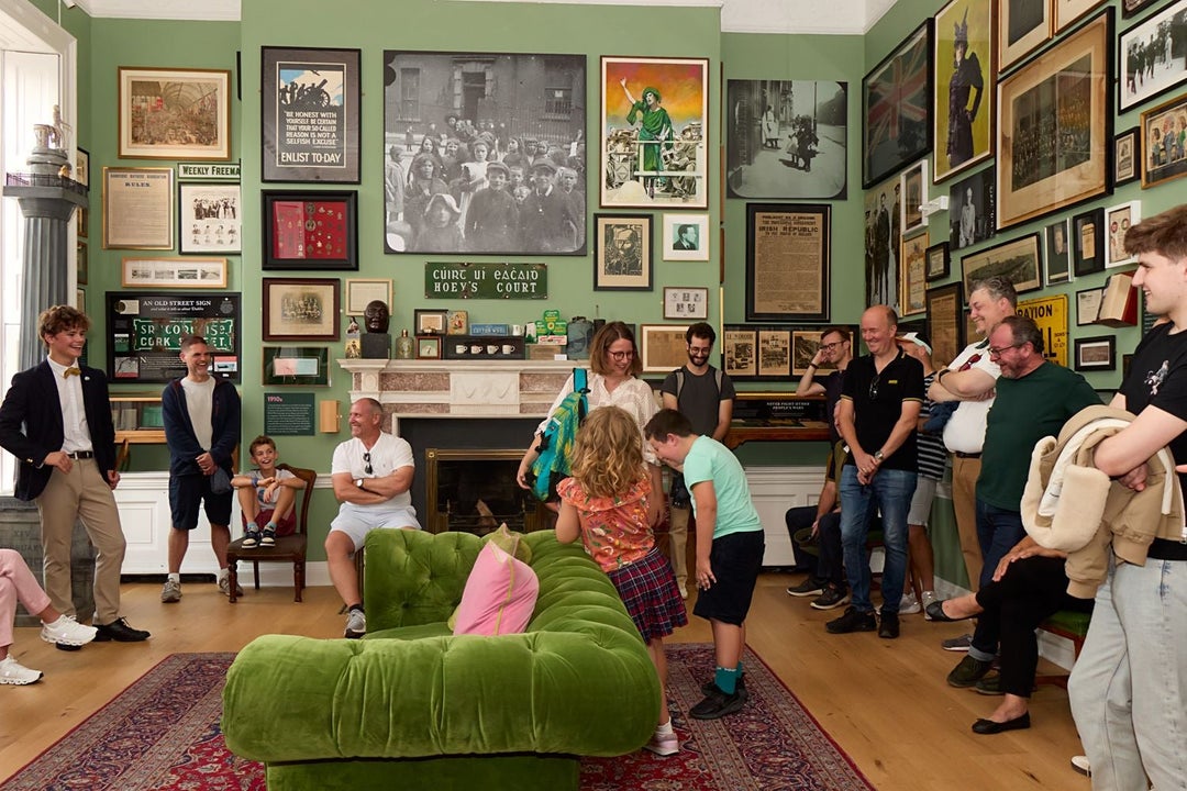 Group of people gathered in a cosy picture filled room listening to a guide