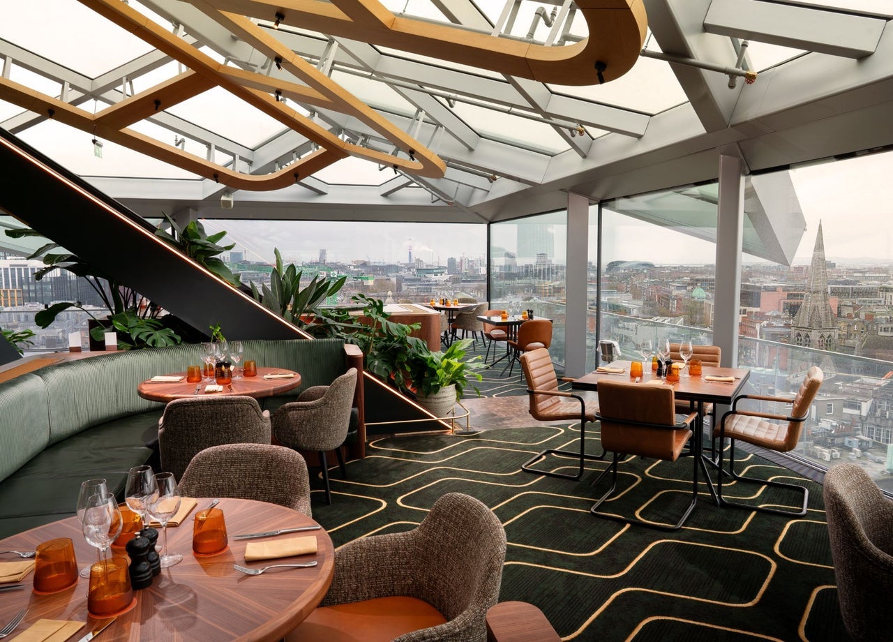 A rooftop dining space with sweeping daytime views across the city skyline