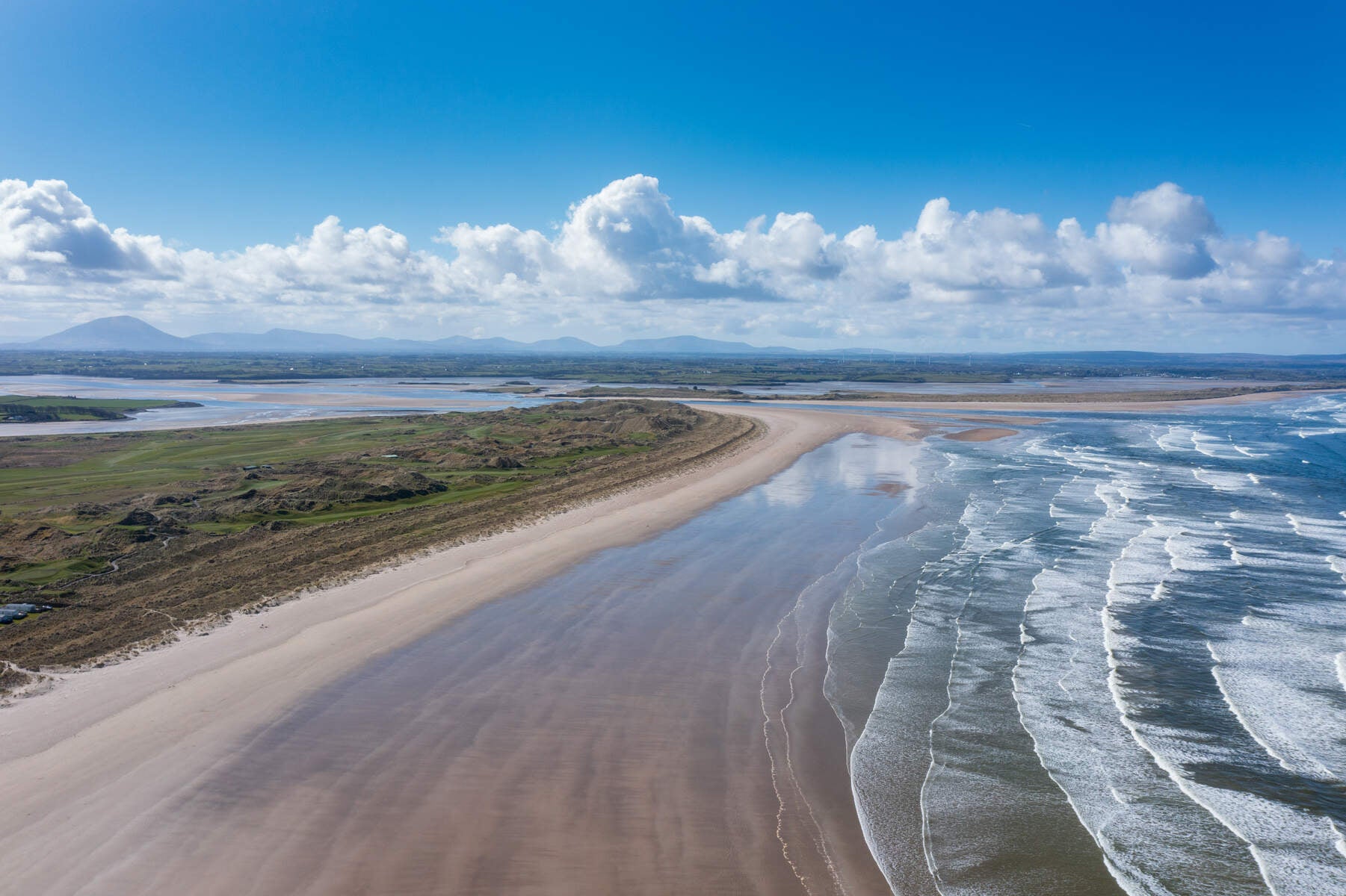 Long sandy beach with the sea and blue sky with white clouds