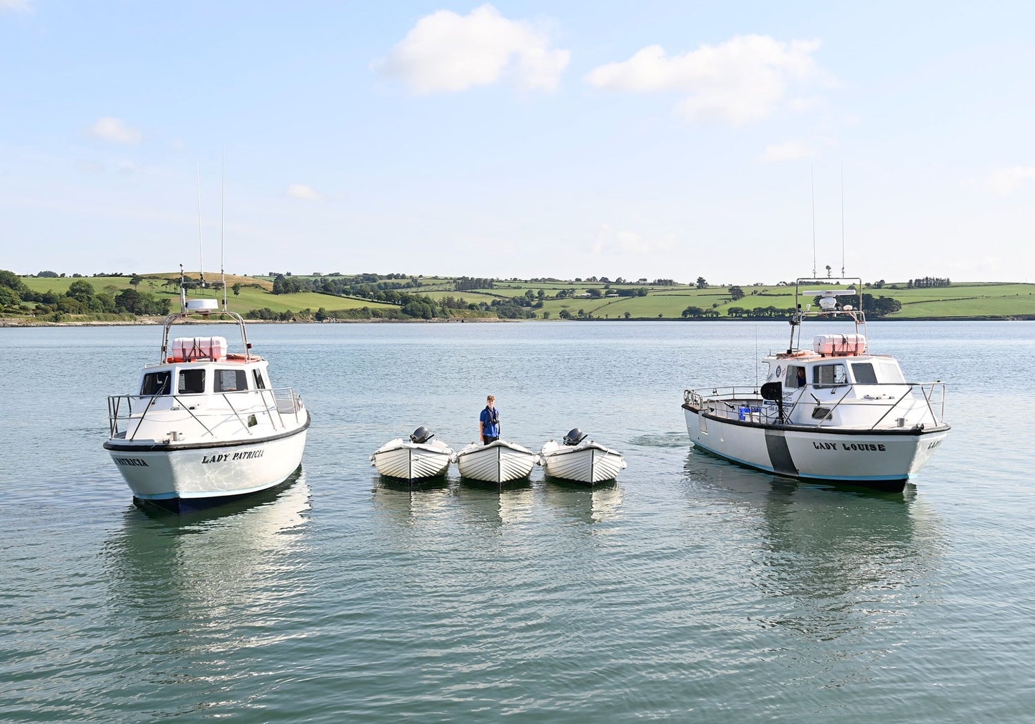 Two small fishing vessels with three smaller self drive boats moored between them