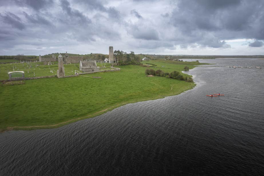 Two people kayaking past ruins on the coastline