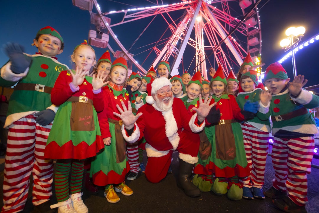Waterford Winterval Festival 2026, a santa kneeling with jazz hands surrounded by children dressed as elves.