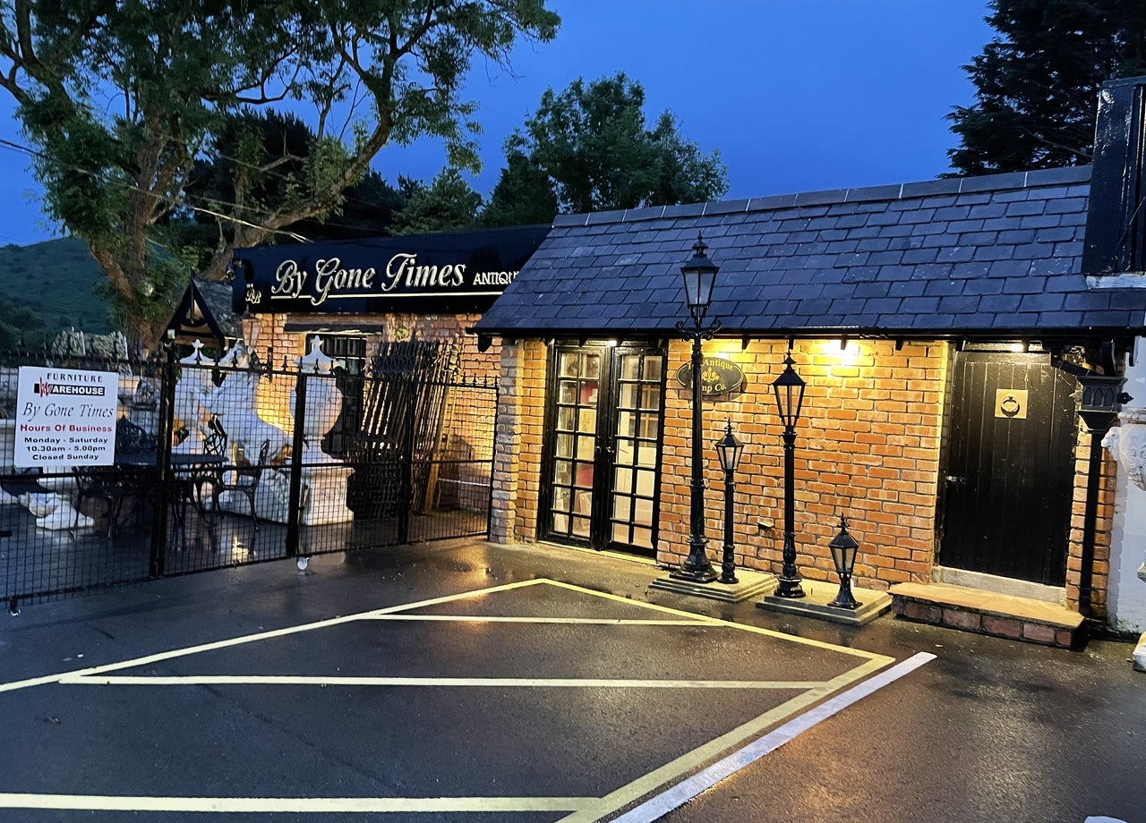An antique shop exterior lit up at dusk with antique lamp posts outside
