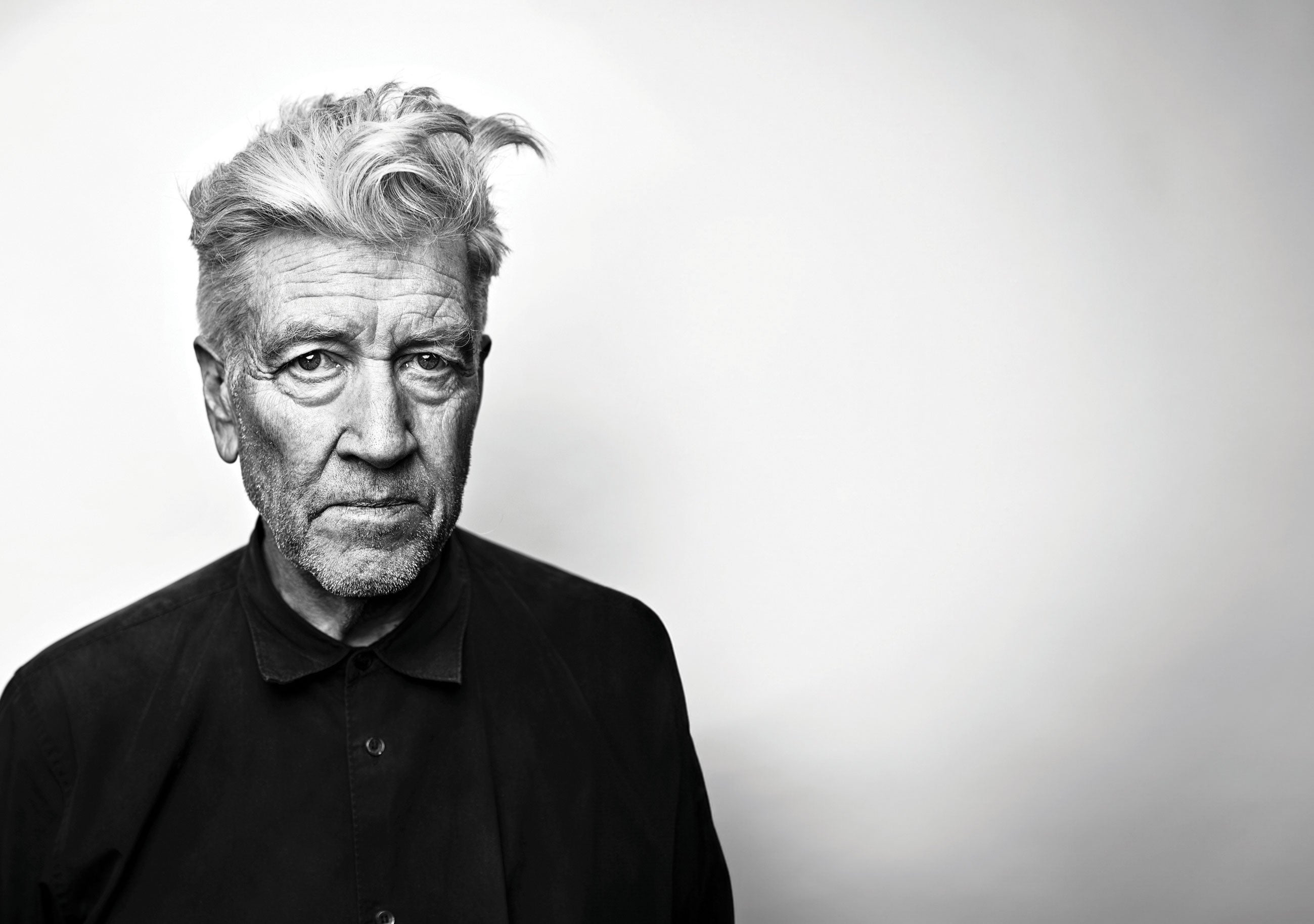 An elderly David Lynch against a blank wall.