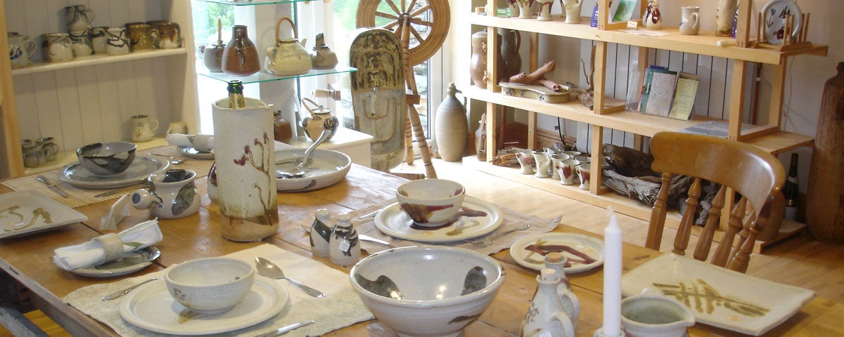 Alan Gaillard Pottery Studio with wooden table and a mix of pottery dishes neatly displayed