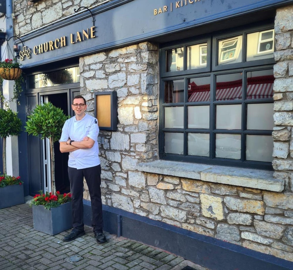 Man in chefs jacket standing outside a restaurant