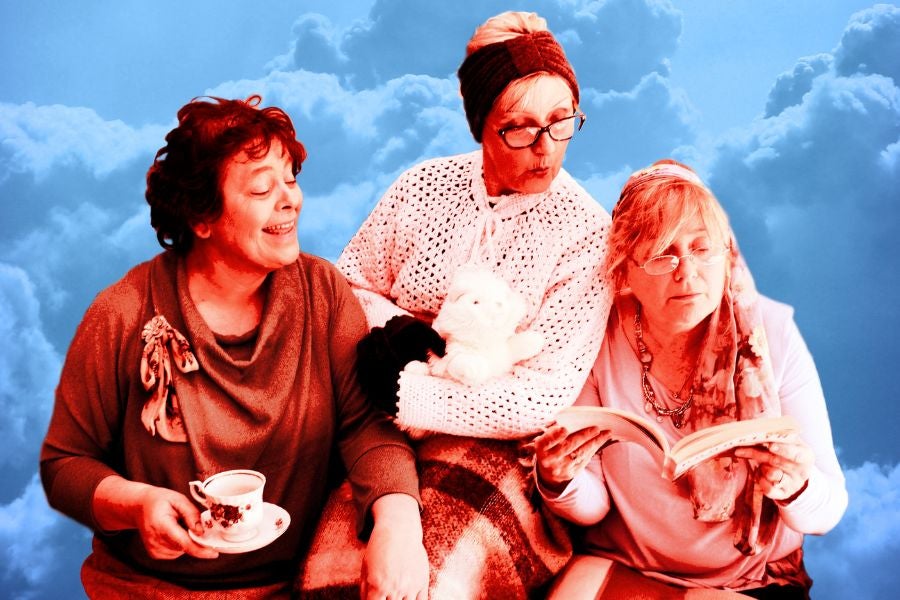 3 older women looking at an open book one of them is holding.