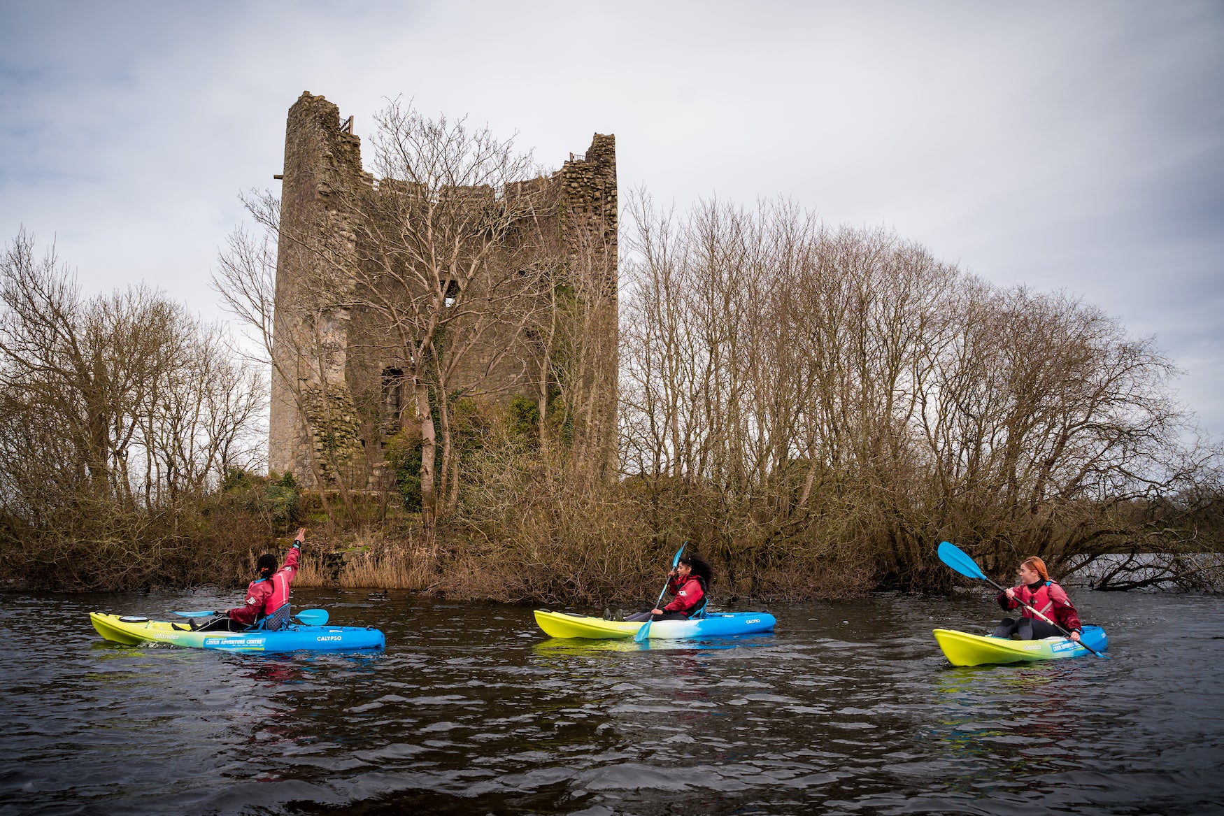People kayaking past Clough Oughter Castle in Cavan