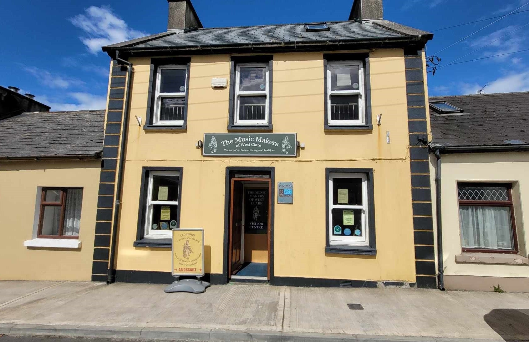 Yellow building on a street with five windows and an open door