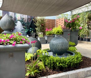 A selection of planters with pink flowers and a water fountain
