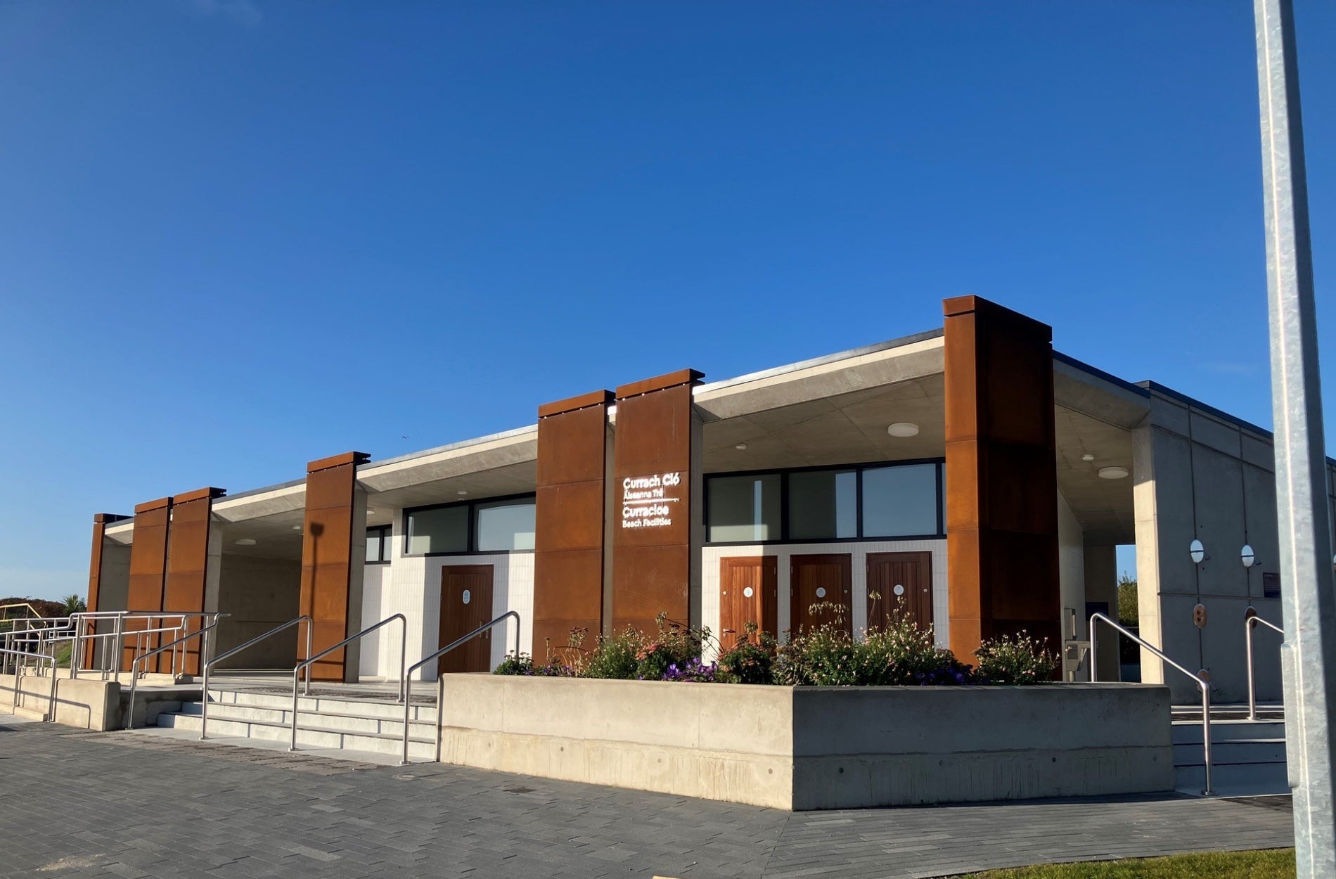 Side view of a modern building with railings and steps and a blue sky overhead