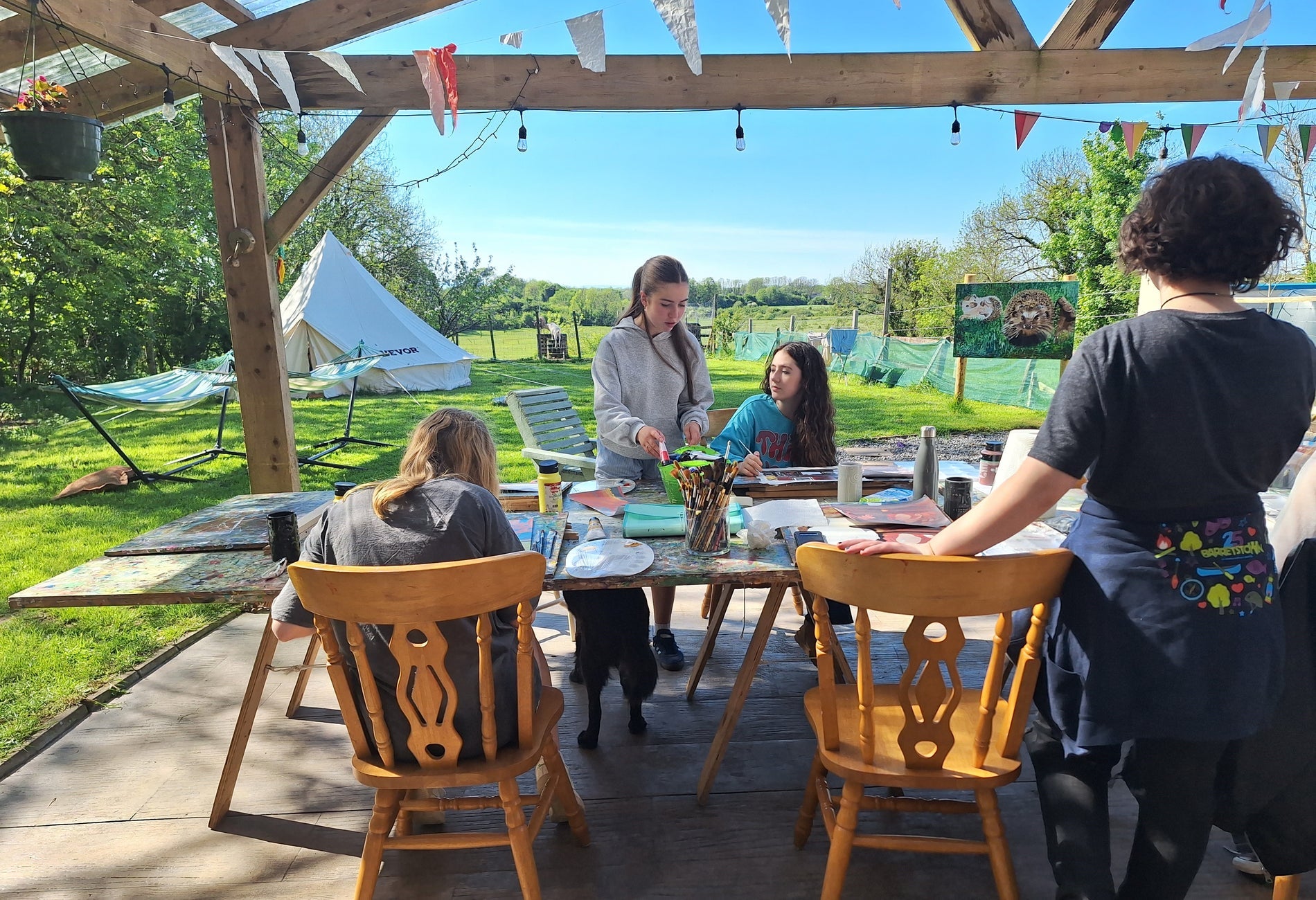 Four people standing around a table with painting materials on a sunny day