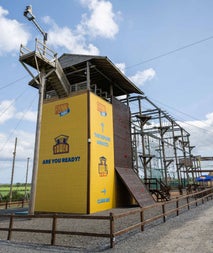 Yellow climbing frame on gravel enclosed by a wooden fence