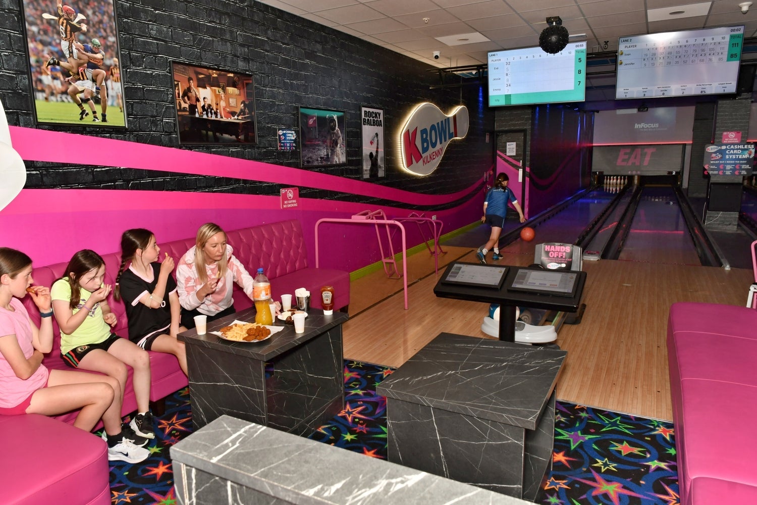 Colourful bowling alley with people sitting while others bowl
