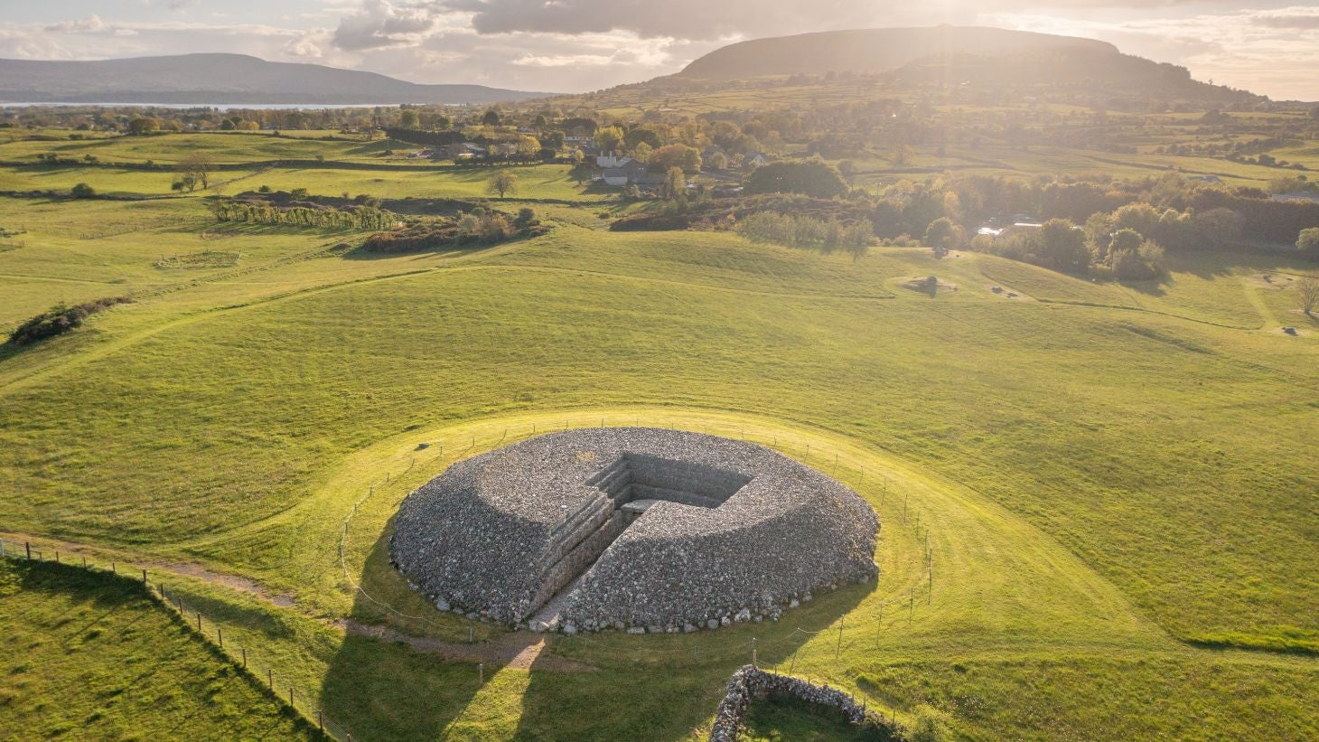 Tombs with mountains and green fields in the background at Carrowmore Megalithic Cemetery, Sligo