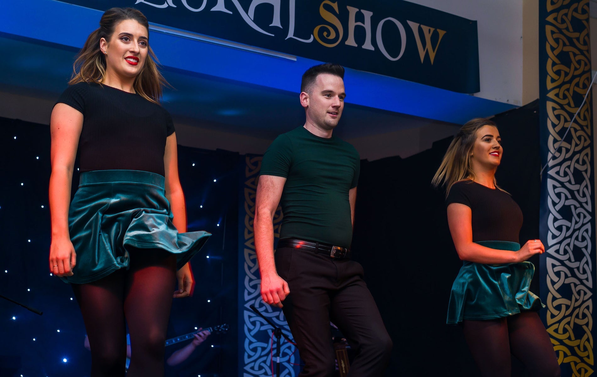 Three people in a line dancing on a stage