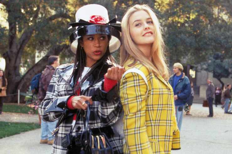 2 young women in different coloured checked outfits standing back to back outdoors