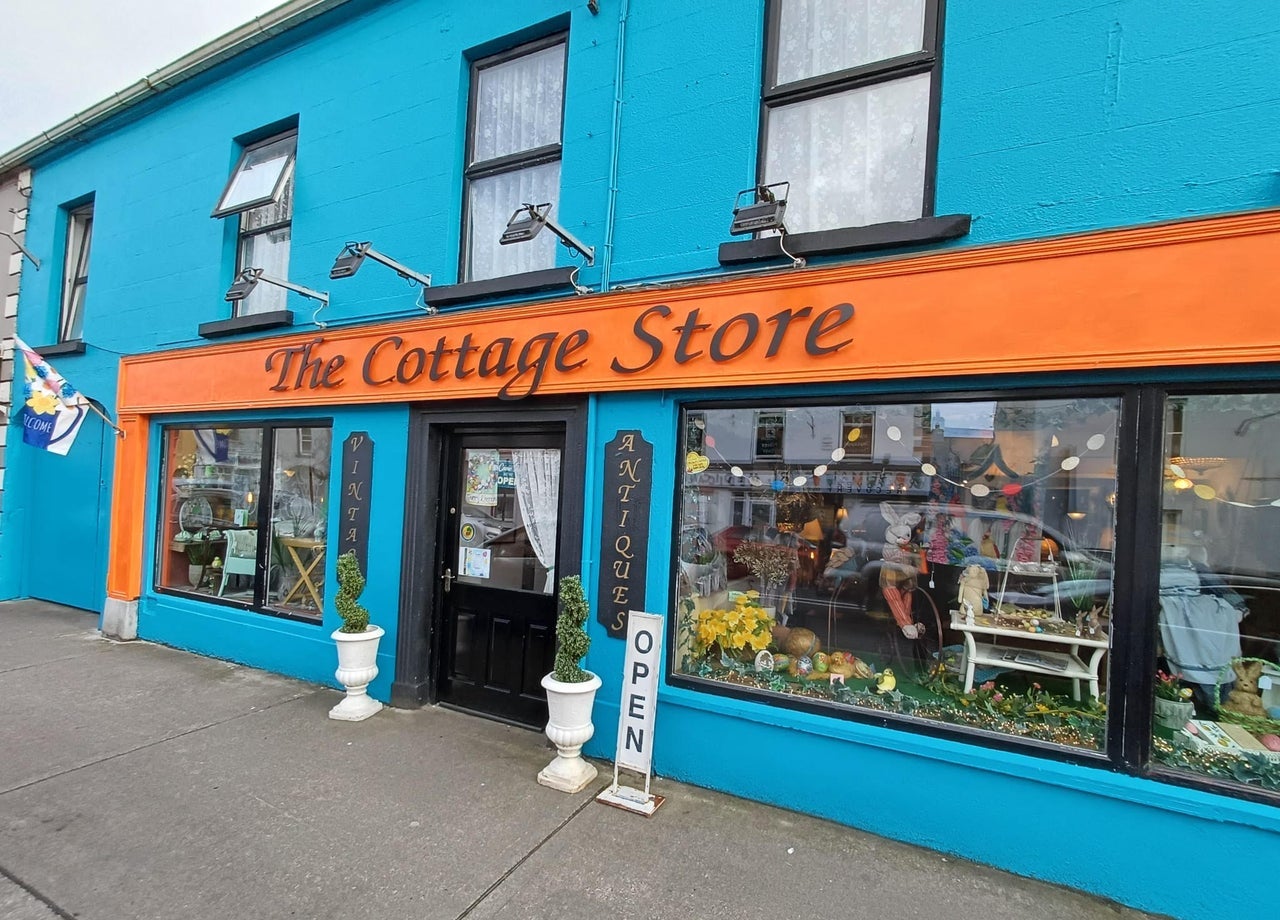 Colourful exterior of a shop with antiques displayed at the windows