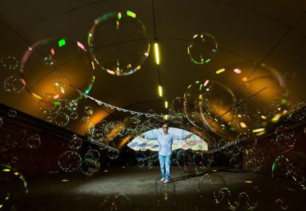Distant view of man with arms outstretched in pale blue with area covered in bubbles of different sizes.