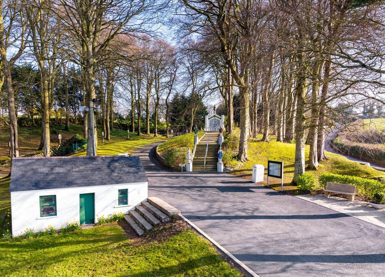 Entrance to a shrine with trees and a miniature traditional cottage