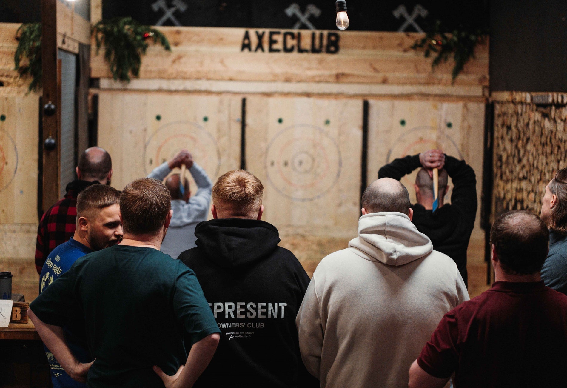 Two people throwing axes as a group of people watch