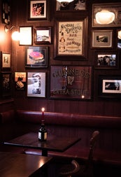 Dark interior of a pub with pictures on the walls and a bottle with a lighting candle on a table