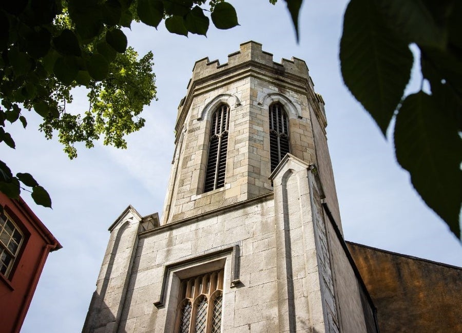 Ground level view of a church next to a red building with trees in the top corners