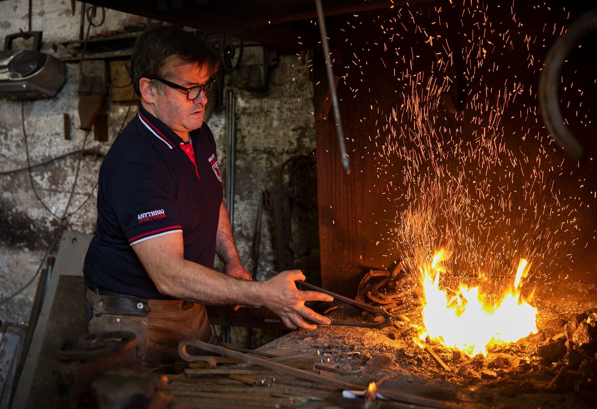 A farrier with a horseshoe heating among the flames