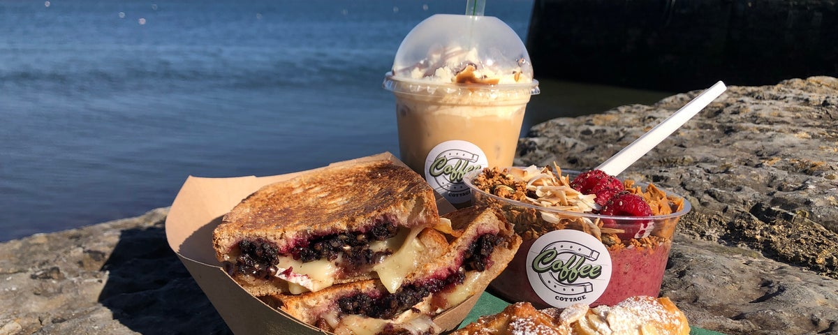 A smoothie, pastry and dessert sitting on a stone wall at Coffee Cottage