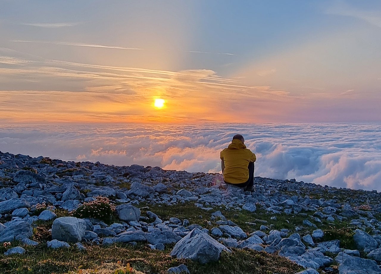 A man sitting watching a sunset while on a night hike with Tonnta Adventure