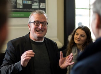 The tour guide smiling while telling his stories to a group of listeners