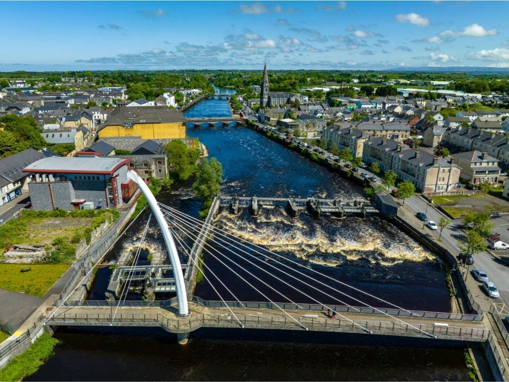 Ariel view of a town with river and modern bridge in the foreground.