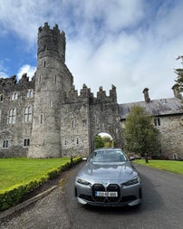 Silver car parked on a driveway with a castle in the background