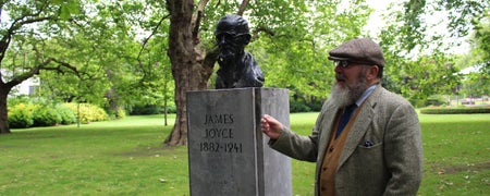 A man standing next to the bust of James Joyce facing Newman House in St Stephens Green