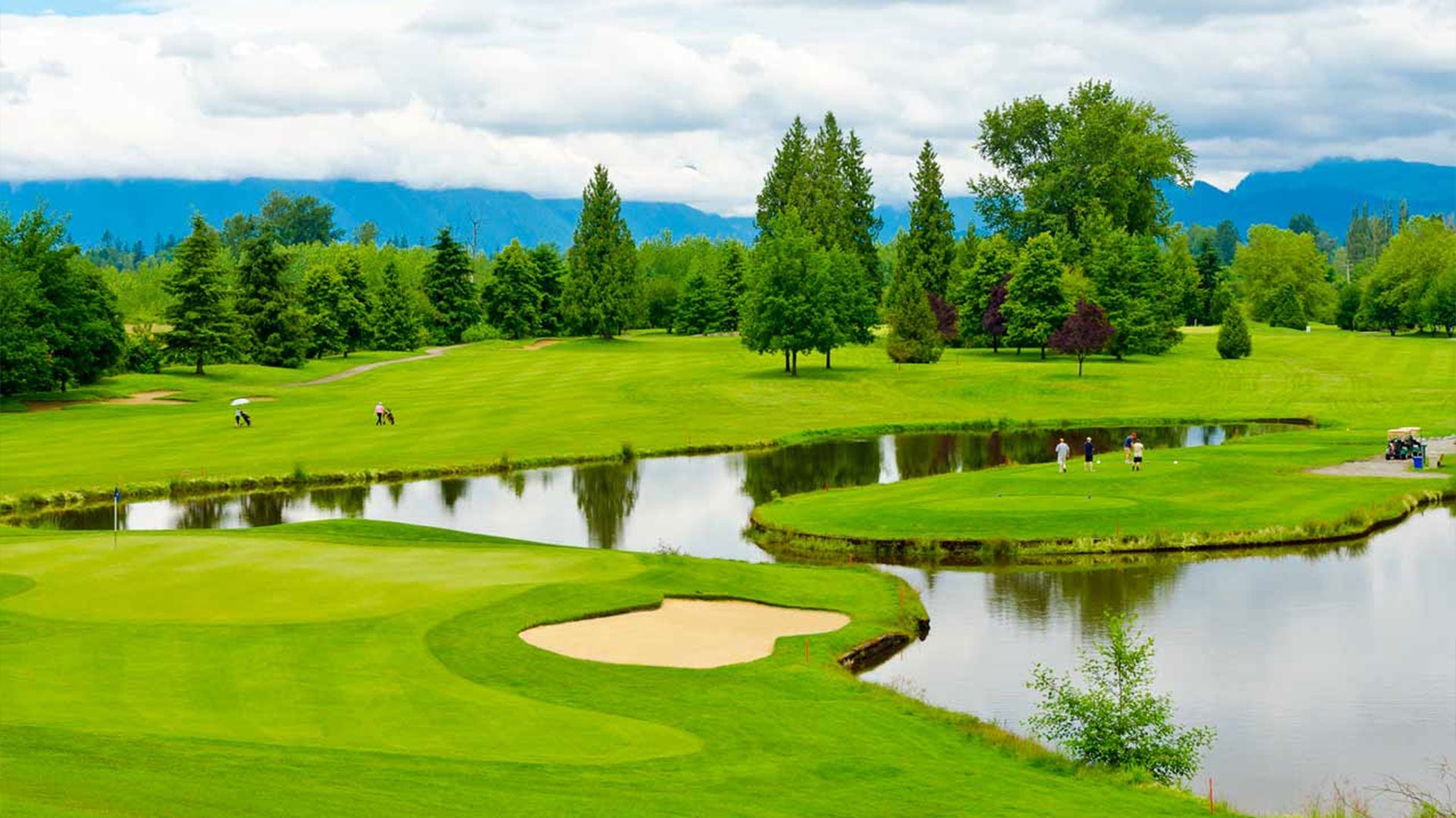 Golf course with trees sand bunkers a lake and players on the green