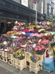 A vibrant Dublin street flower stall bursts with roses, tulips, hydrangeas and sunflowers, wrapped and ready for eager buyers—a fitting symbol of romance in a city with an unexpected connection to the patron saint of love.