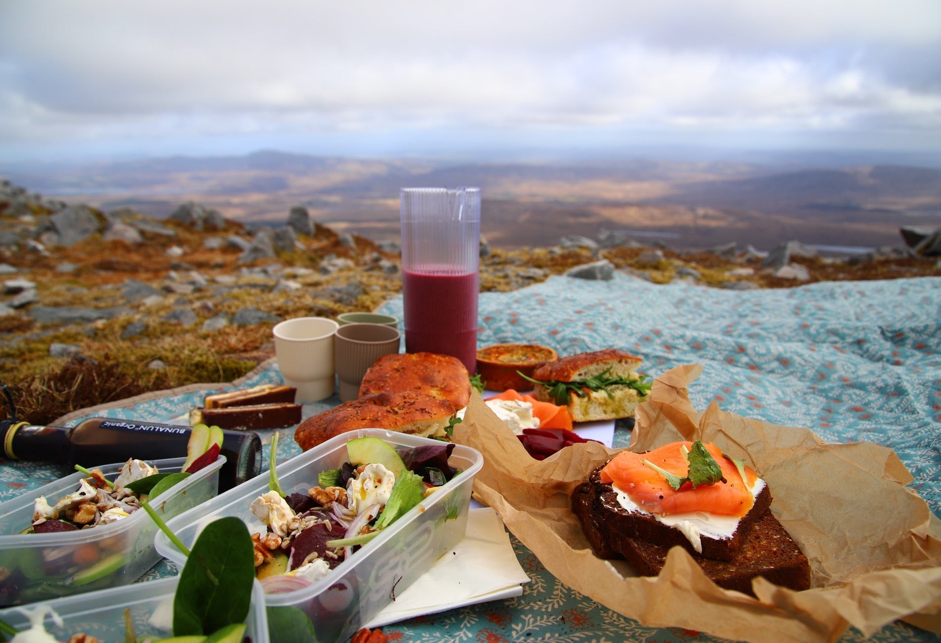A picnic laid out on a blue blanket with mountains in the background