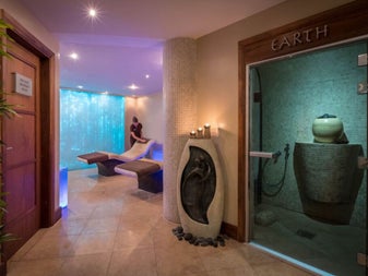 Massage therapist neatening a treatment bed in a spa room