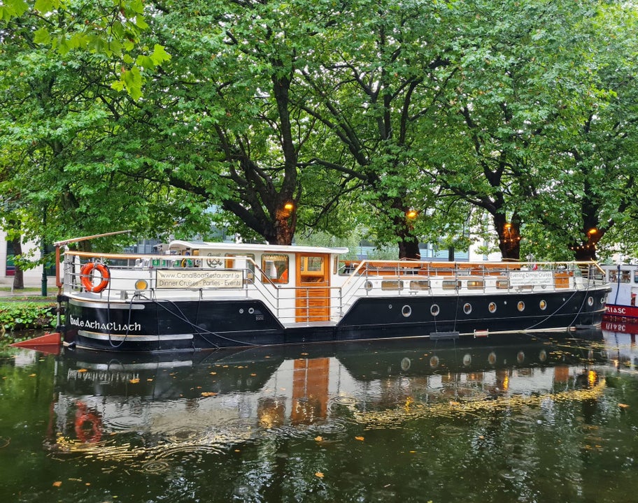 Canal barge moored on a tree lined section of a canal
