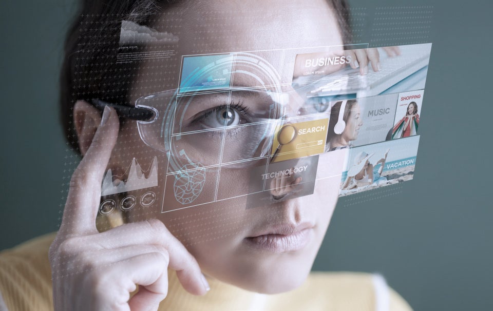 Person using augmented reality glasses with a digital interface displaying content, analytics, and search tools.