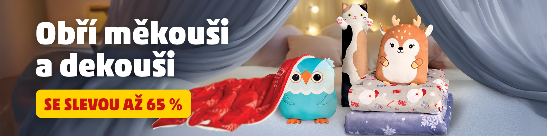 Banner s nabídkou na obří měkké plyšáky a deky se slevou až 65 %. Na obrázku jsou zobrazeny plyšové postavičky (sova, kočka, jelen) a několik dek ve vánočních motivech. Text na banneru zní 'Obří měkouši a dekouši se slevou až 65 %'.